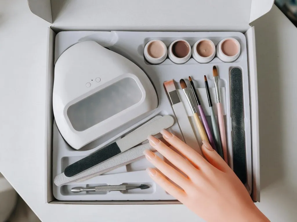 Kit aperto con lampada LED, vasetti di gel, pennelli, lime e una mano di allenamento