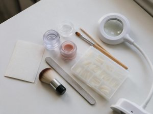 Cartine, gel costruttore, pennello, tips, lima, spolverino e lampada su un tavolo bianco